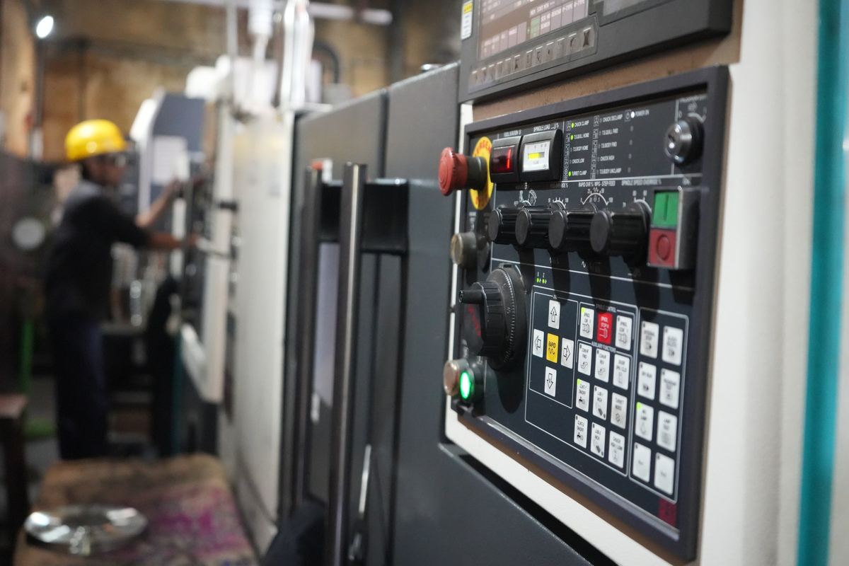 CNC lathe control panel with an operator in the background
