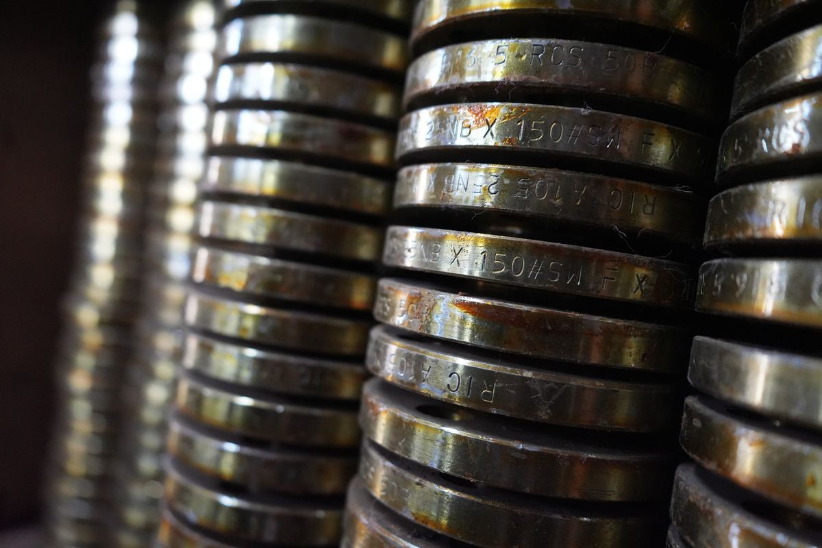 Carbon steel flanges stacked on a shelf showing stamped size and specification markings