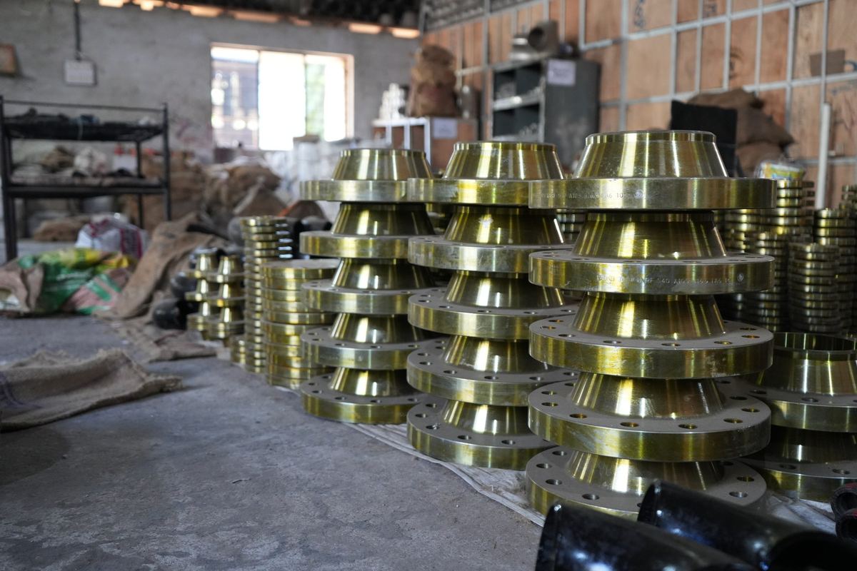 Stacks of carbon steel weld neck flanges with yellow rust preventive coating in the RIC yard