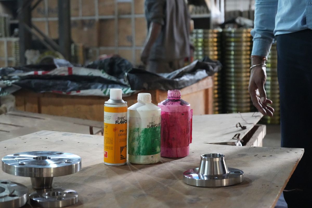 Stainless weld neck flanges on a table with dye penetrant cleaner, penetrant and developer