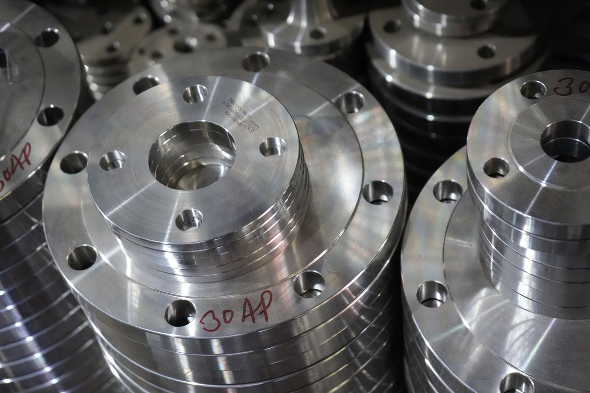 Machined stainless steel plate flanges stacked on a pallet